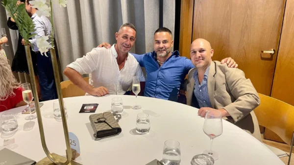Three men seated together at a table during an event.