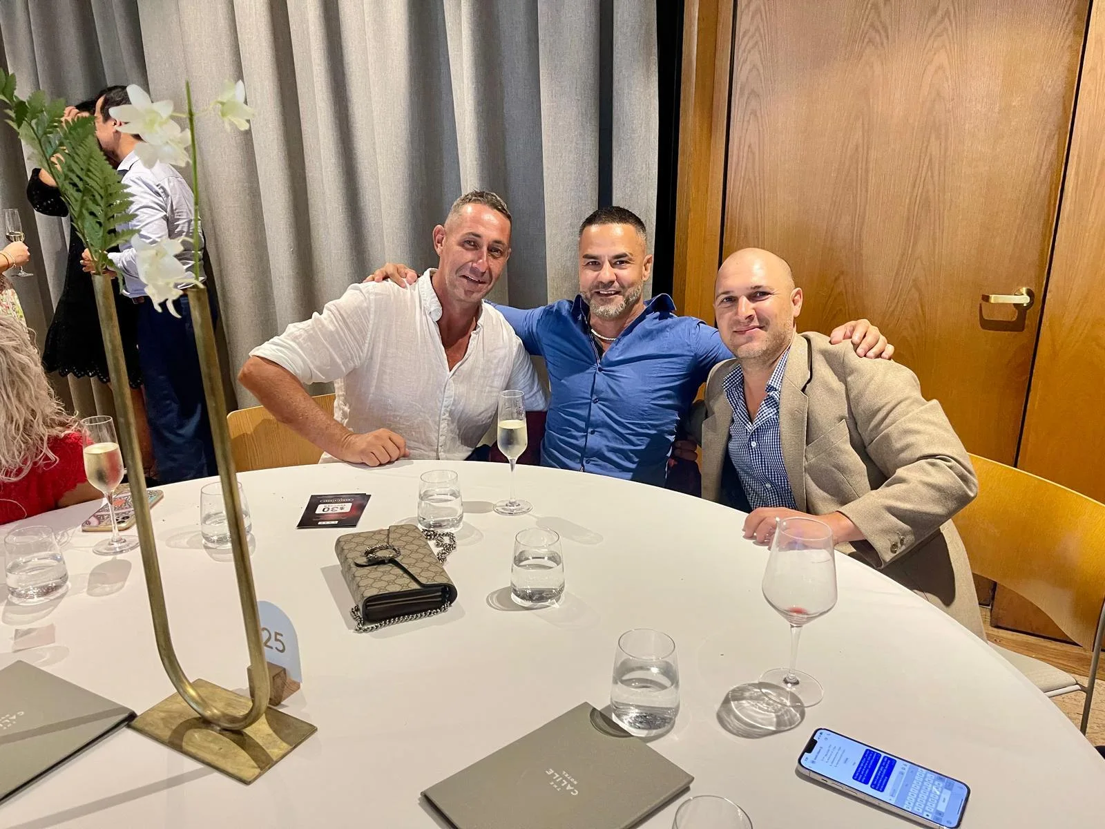 Three men seated together at a table during an event.